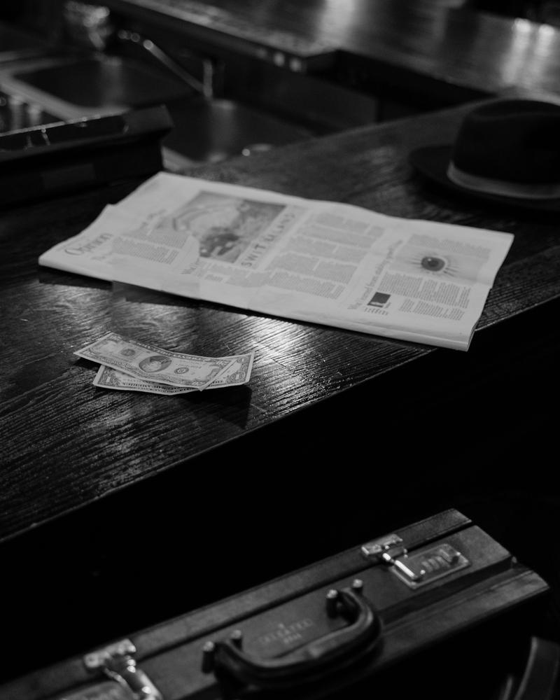 Bar counter in dark wood with a newspaper, a few banknotes and a hat