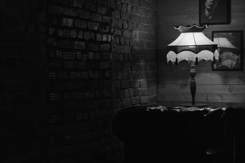 Fringed table lamp lighting a corner with a brick wall and a leather sofa