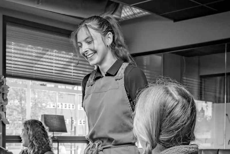 A smiling server in an apron by the windows at Raus