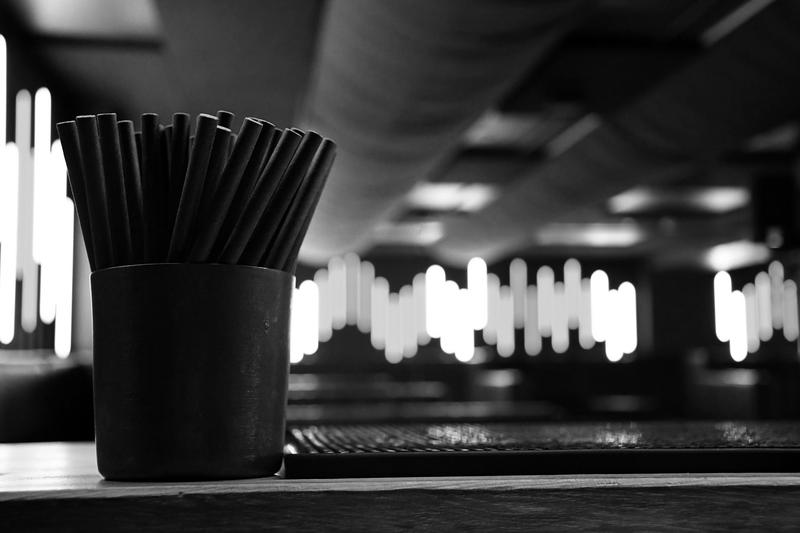 Straws in a cup on the counter, with the light columns at Tåkt behind